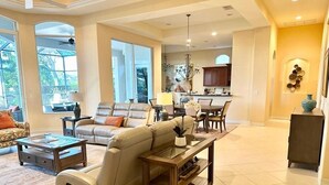 A spacious living room with a leather sofa, a coffee table, and a dining area with a chandelier.
