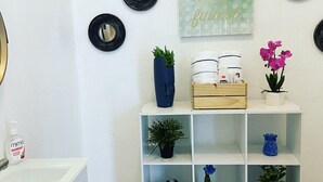 A bathroom with a white sink, a mirror, and a shelf with toiletries and decorative items. - studio apartment near to airport (Carolina)