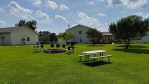 Un espacio al aire libre con césped, mesas y sillas de picnic, rodeado de edificios.