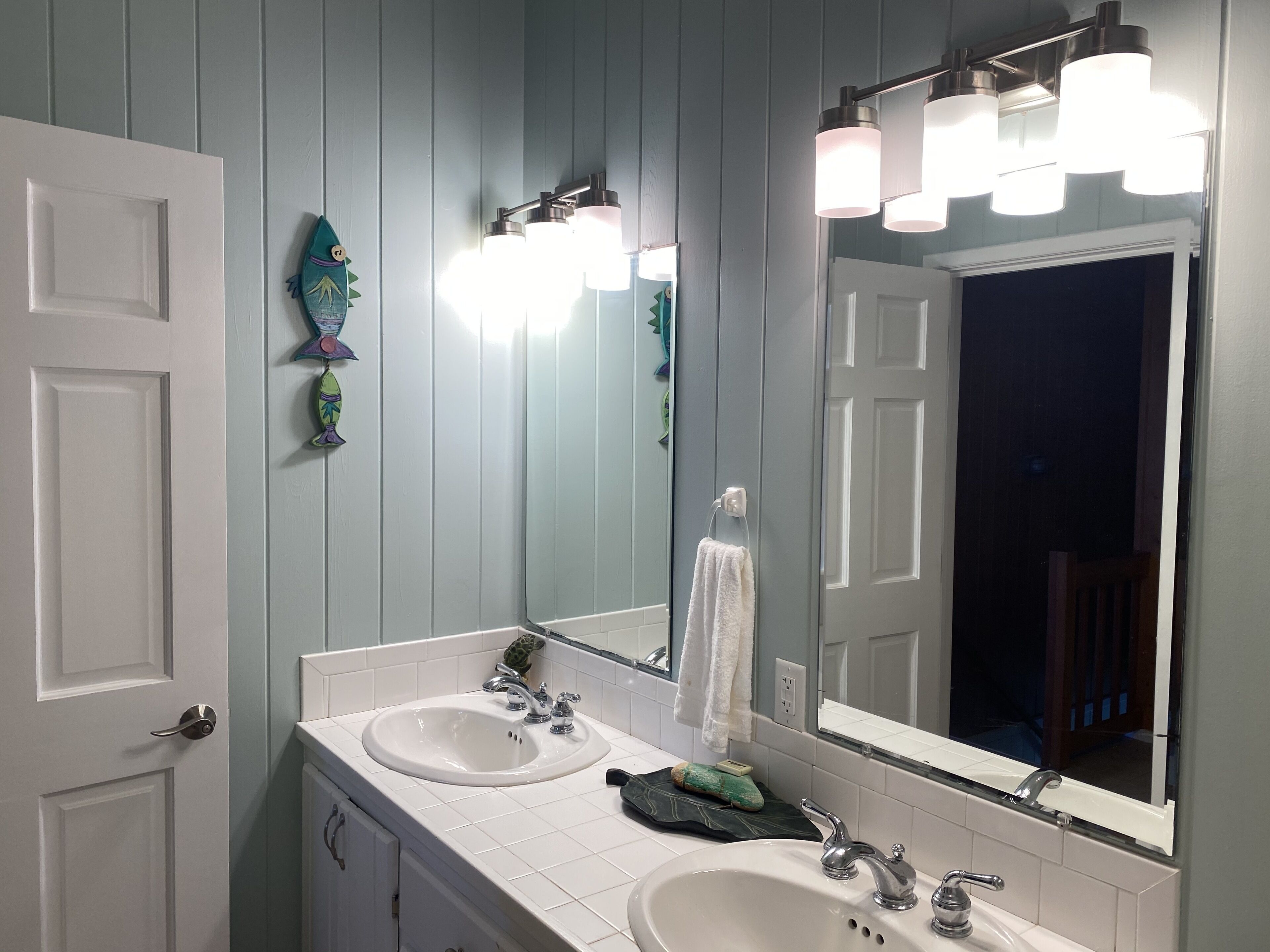 A bathroom with two sinks, a large mirror, and wall-mounted lights.