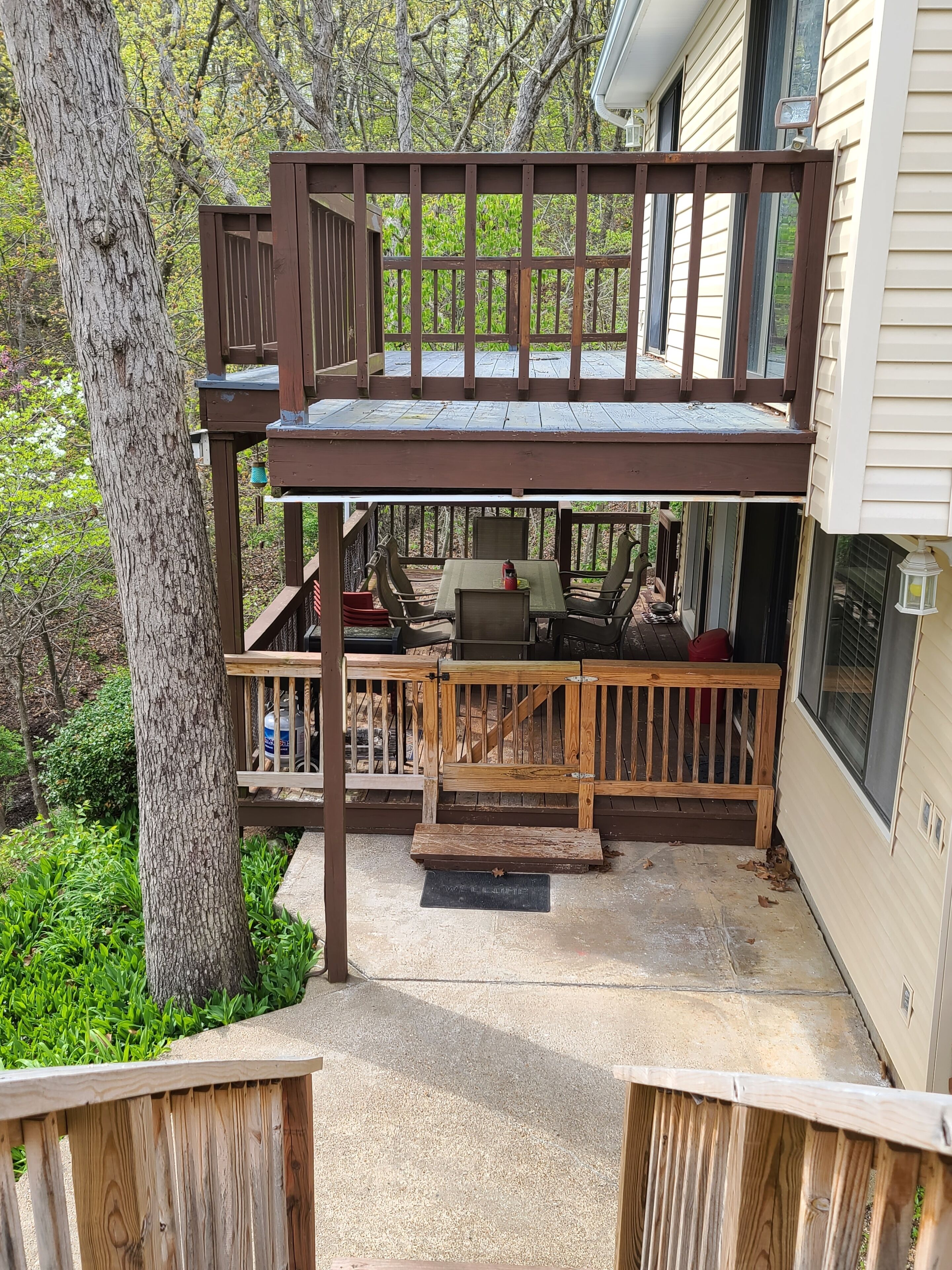 A deck with a table and chairs, a barbecue grill, and a wooden bench.
