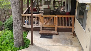 Una terraza con una mesa, sillas, una parrilla y un banco de madera.
