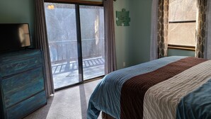 Un dormitorio con cama, cómoda, ventilador de techo y ventana con cortinas.