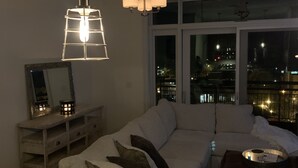 Una sala de estar moderna con un sofá modular, una mesa de comedor y un amplio ventanal con vistas a la ciudad.