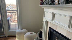 Una sala de estar con chimenea, un tapete blanco y un pequeño árbol de Navidad.