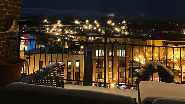 Un balcón con vistas a un edificio y farolas iluminando la calle por la noche.
