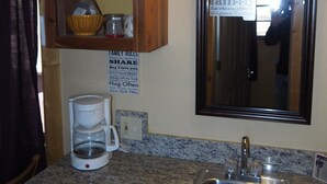 A kitchen with granite countertops, a coffee maker, a sink, and a framed family rules sign. - NEW!  Village of Hope - Cabin #12 (Ava)