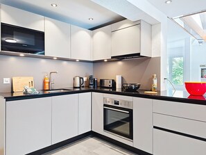 A modern kitchen with white cabinetry, a black countertop, a Siemens microwave, a coffee maker, a toaster, and a red bowl. - Belvedere by Interhome (Brienz)
