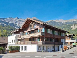 A multi-story building with balconies, a ski slope in the background, and a mountain range. - Belvedere by Interhome (Brienz)