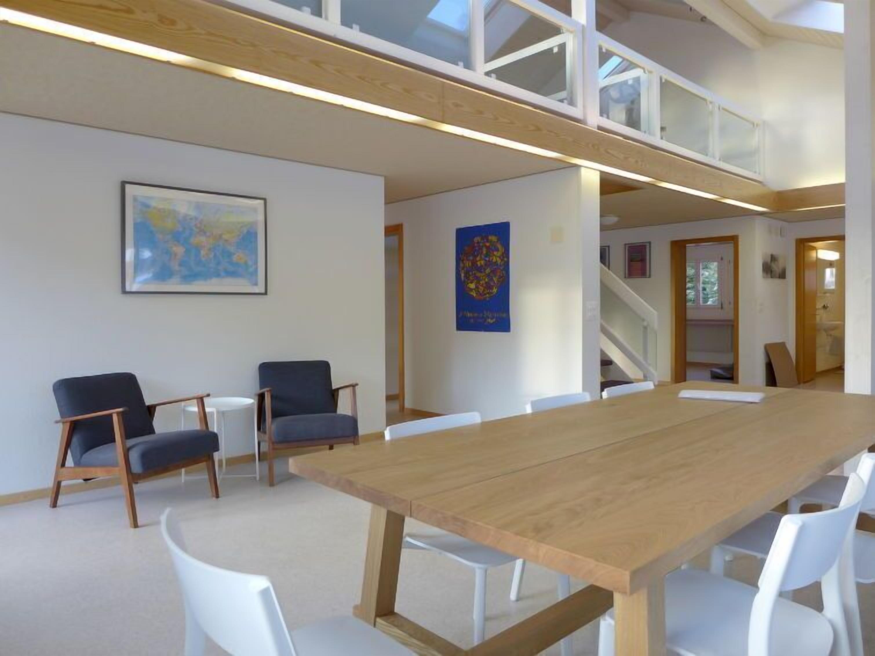 Een vergaderzaal met een lange houten tafel, witte stoelen en een kaart aan de muur.