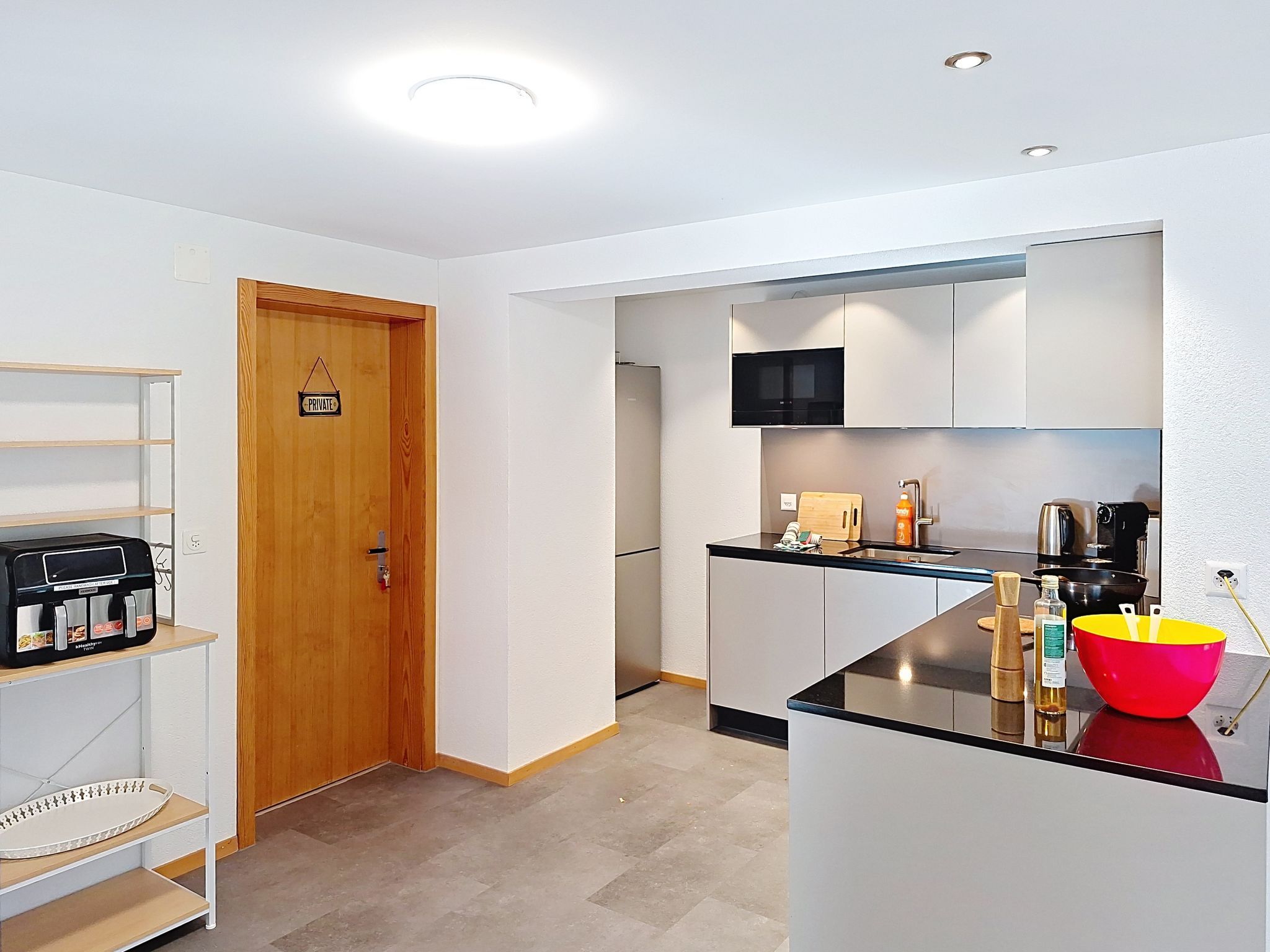 Una cocina moderna con microondas, tostadora y un tazón rojo sobre la encimera.
