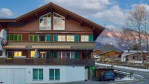 Eine zweistöckige Chalet mit geneigtem Dach, großen Fenstern und einem Balkon.