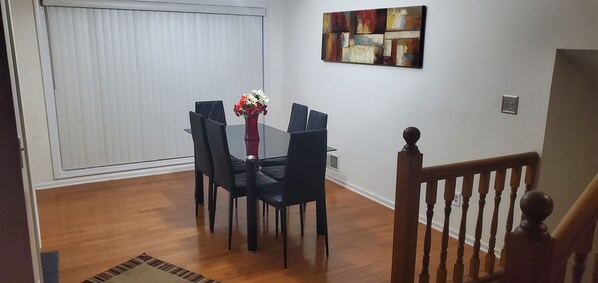 A dining area with a glass table, black chairs, and a vase with flowers. - Welcoming Quaint Home (Stone Mountain)