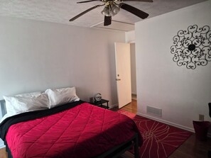 A bedroom with a bed, a ceiling fan, a door, and a decorative wall piece. - Welcoming Quaint Home (Stone Mountain)