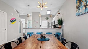 Un comedor moderno con una mesa de madera, taburetes de bar azules e iluminación colgante.