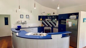 A modern kitchen with a curved island, stainless steel appliances, and a blue backsplash. - La Block Yallingup simply the best! (Yallingup)