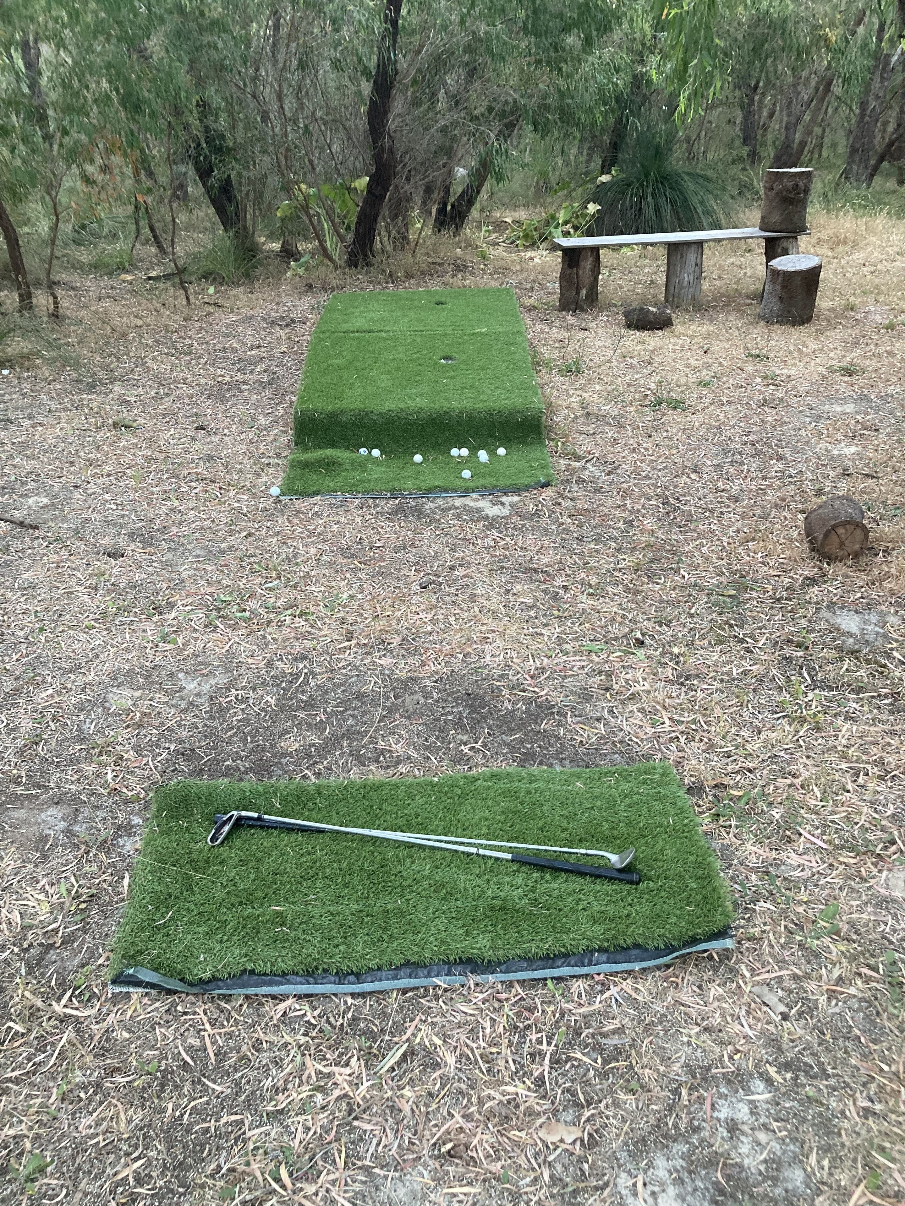 Un campo de práctica de golf con un putter y pelotas.