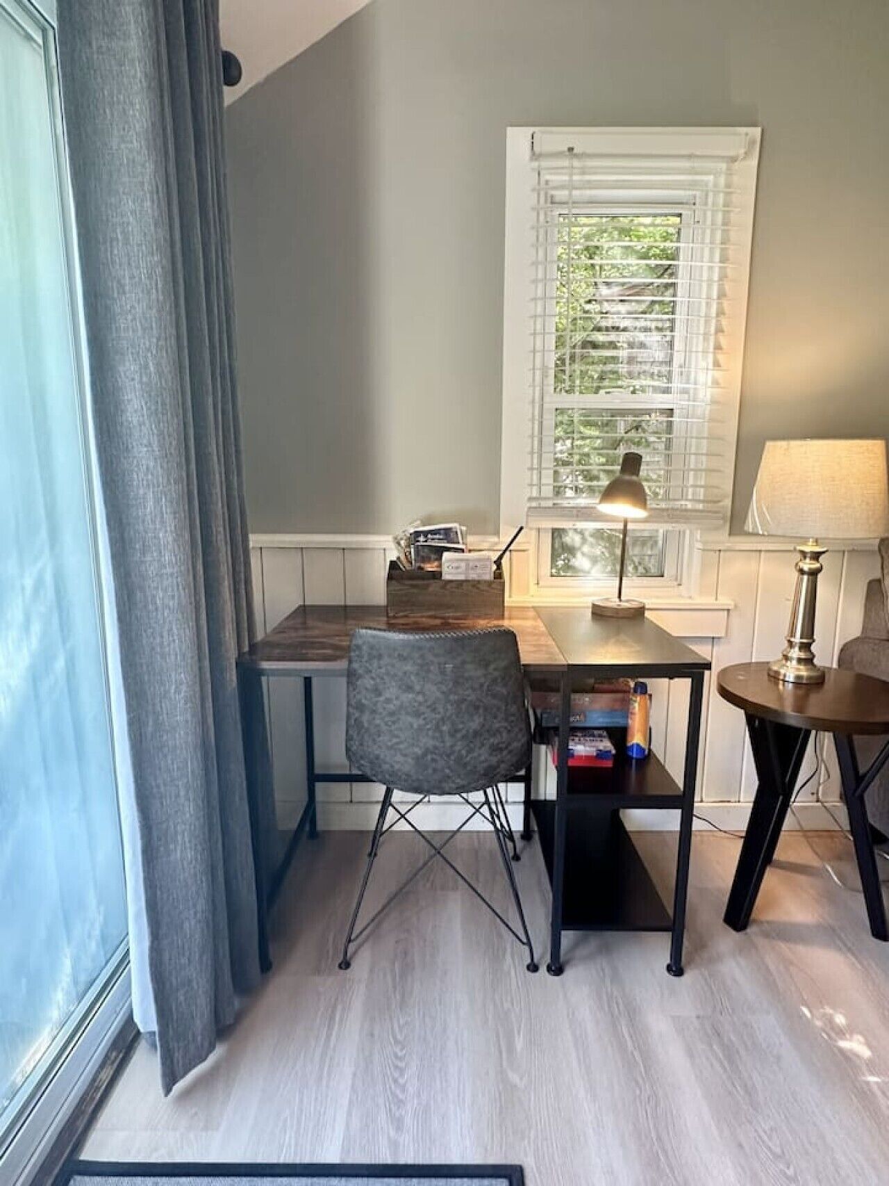 A small, well-lit room with a desk, chair, and two lamps.