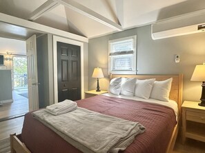 Ein Schlafzimmer mit einem Bett, zwei Nachttischen, einem Fenster und einer Tür.
