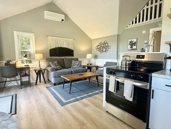 A modern kitchen with a built-in oven and a dining area with a sofa and coffee table.