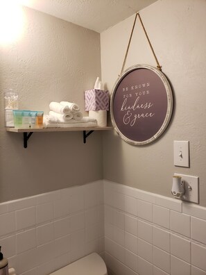 Bathroom features a clean design with a white toilet, towel rack, and toiletries.