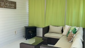 A covered porch with a wicker sofa, a glass coffee table, and a ceiling fan.