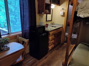 A compact kitchen with a microwave, sink, and wooden cabinets. - NEW!  Village of Hope - All 6 Cabins (Ava)