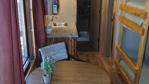 A compact room with a wooden table and chairs, a small sink, and a shower area. - NEW!  Village of Hope - All 6 Cabins (Ava)