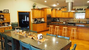 A spacious kitchen with granite countertops, wooden cabinets, and a central island with stools. - NEW!  Village of Hope - All 6 Cabins (Ava)