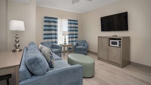 Un salon moderne comprenant un canapé, des fauteuils, une petite table, une lampe, un téléviseur et un four à micro-ondes.