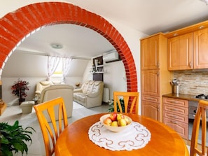 A modern living room with a dining area, a kitchen with wooden cabinets, and a red brick archway. - Apartment Gabor by Interhome (Siofok)