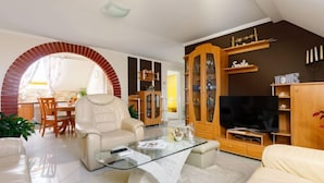 A modern living room with a glass coffee table, leather sofa, and a TV.