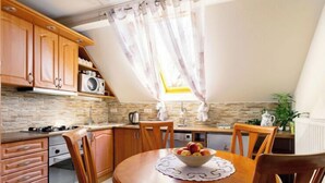 A cozy kitchen with wooden cabinets, a round dining table with chairs, and a fruit bowl.