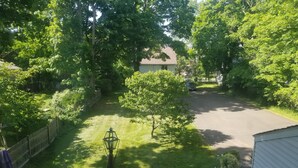 Ein Wohngrundstück mit Rasen, einer Holzdielen-Terrasse und einem Haus im Hintergrund.
