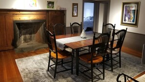 Ein Esszimmer mit Holztisch, sechs Stühlen, Kamin und Bildern an den Wänden.
