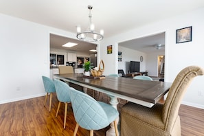 A modern dining area with a large rectangular table, light blue upholstered chairs, and a chandelier.