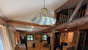 A wooden interior with a dining table, chairs, a sofa, and a kitchen area. - Escape to Priest Lake! Cabin in the woods! Air Conditioning and WiFi!! (Nordman)
