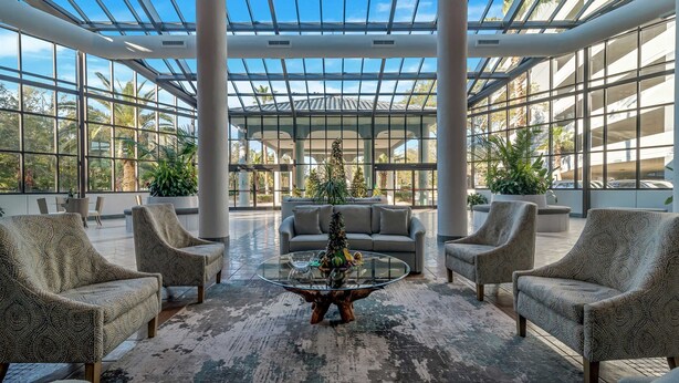 A spacious indoor area with a glass ceiling, large windows, and comfortable seating.