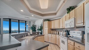 A modern kitchen with a large island, built-in appliances, and a view of the sea.