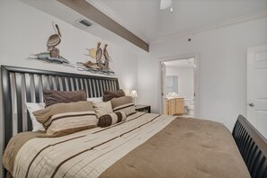 A bedroom with a large bed, a wooden headboard, and a wall-mounted artwork of birds. - Lighthouse on the Bay 2302 | Lazy River | Boat Slip | My Beach Getaways (Orange Beach)
