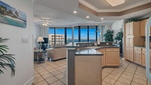 A modern kitchen with a large island, wooden cabinets, and a view of the ocean.