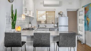 A modern kitchen with a central island, bar stools, a clock, and a world map on the wall. - Beachfront self contained upstairs apartment (Semaphore)