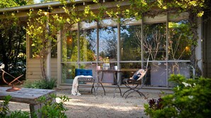 Cómoda zona de estar al aire libre con una mesa y sillas, rodeada por una pérgola cubierta de plantas trepadoras.