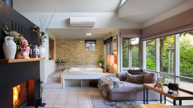 Un interior moderno con una pared de piedra, un ventanal grande, una chimenea y una zona de estar acogedora.