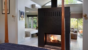 Una sala de estar moderna con chimenea, un ventanal y vistas al exterior.