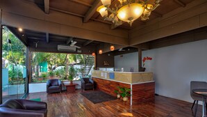 A modern reception area with a wooden floor, leather seating, and a reception desk. - Aqua Marina Beach Cottages (Candolim)