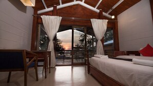 A bedroom with a wooden ceiling, a bed, a desk, and curtains. - Aqua Marina Beach Cottages (Candolim)
