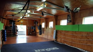 A spacious gym with wooden walls, a black mat with 'Boxer' branding, and various boxing equipment. - With the lake on your doorstep, BEACH 2 minutes away and river swimming hole . (Opunake)