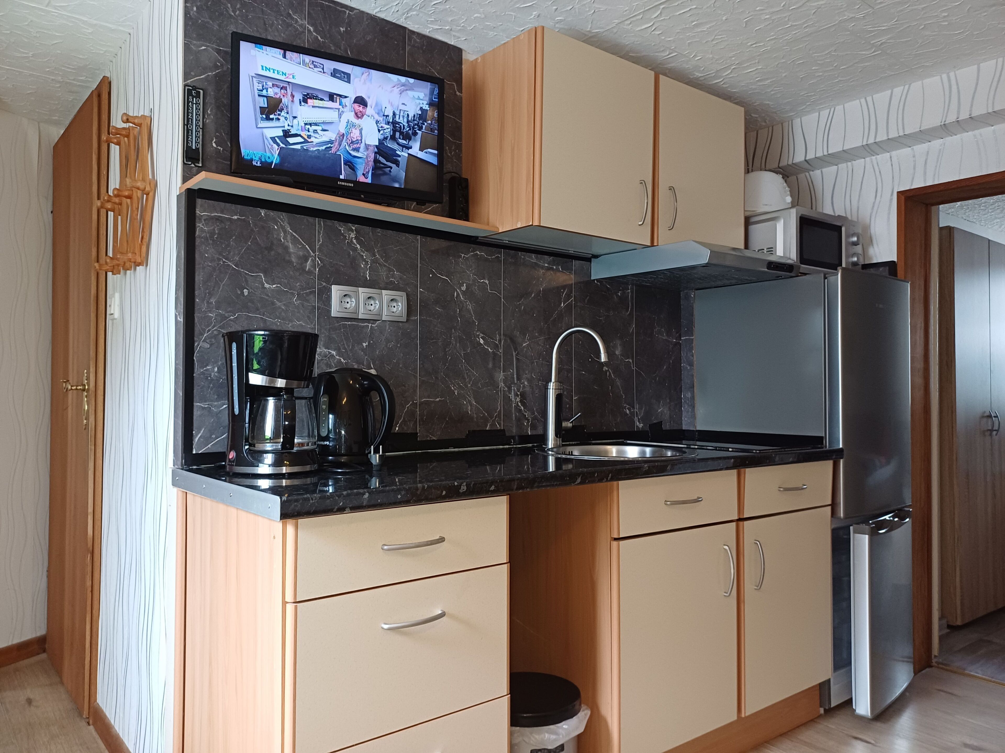 Eine moderne Küche mit integriertem Fernseher, Edelstahlgeräten und Holzschränken.