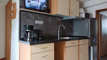 Eine moderne Küche mit integriertem Fernseher, Edelstahlgeräten und Holzschränken.